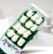 Caja rectangular con 12 rosas blancas sobre fondo verde y logo Feria de Flores