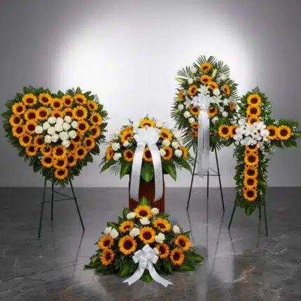 Arreglos fúnebres de girasoles amarillos y flores blancas en forma de corazón, cruz, coronas y centro floral sobre caballetes en una sala velatoria