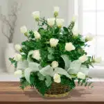 Arreglo floral de rosas blancas en canasta de mimbre sobre mesa de madera