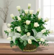 Arreglo floral de rosas blancas en canasta de mimbre sobre mesa de madera