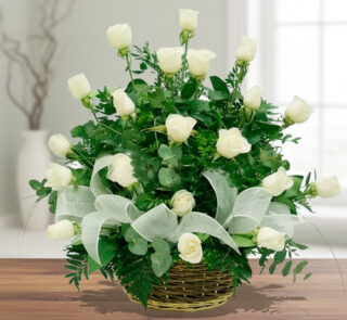 Arreglo floral de rosas blancas en canasta de mimbre sobre mesa de madera