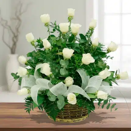 Arreglo floral de rosas blancas en canasta de mimbre sobre mesa de madera