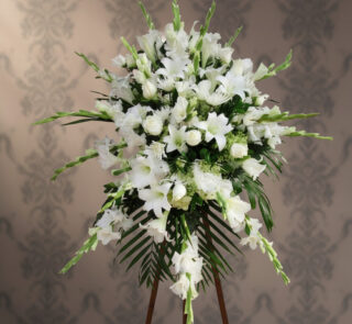 Arreglo floral grande de flores blancas con lirios y rosas sobre caballete de madera