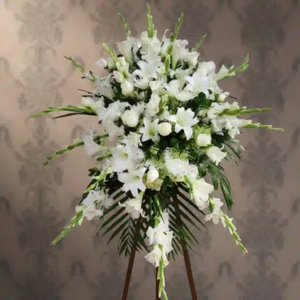 Arreglo floral grande de flores blancas con lirios y rosas sobre caballete de madera