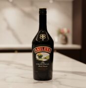 Botella de licor Baileys The Original Irish Cream negra sobre encimera de mármol en cocina desenfocada