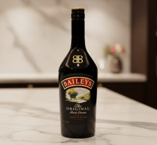 Botella de licor Baileys The Original Irish Cream negra sobre encimera de mármol en cocina desenfocada