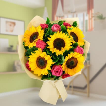 Ramo de flores con girasoles amarillos y rosas rosas envuelto en papel beige sobre fondo de salón desenfocado