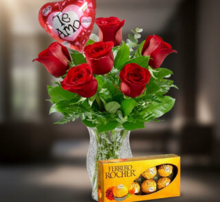 Ramo de rosas rojas en florero de cristal con globo de corazón que dice te amo y caja de chocolates Ferrero Rocher al frente