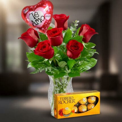 Ramo de rosas rojas en florero de cristal con globo de corazón que dice te amo y caja de chocolates Ferrero Rocher al frente