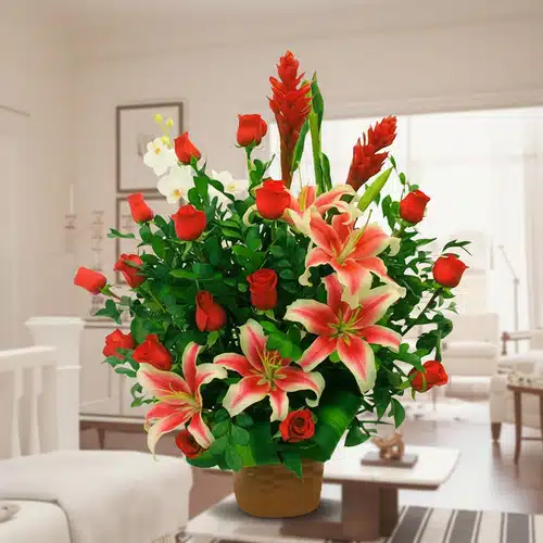 Arreglo floral de lirios y rosas rojas en sala de estar Arreglo de flores con lirios rosados y blancos y rosas rojas en maceta marrón sobre mesa en una sala de estar luminosa