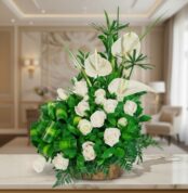 arreglo floral con rosas blancas y anturios blancos en base de madera sobre mesa de mármol en sala elegante