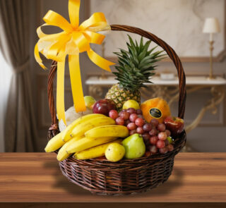 canasta de mimbre con plátanos, uvas, piña, peras y otras frutas variadas decorada con gran lazo amarillo sobre mesa de madera en interior elegante