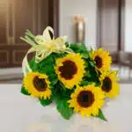 Ramo de girasoles amarillos con lazos decorativos sobre una mesa blanca en interior elegante