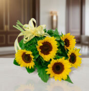 Ramo de girasoles amarillos con lazos decorativos sobre una mesa blanca en interior elegante