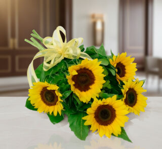 Ramo de girasoles amarillos con lazos decorativos sobre una mesa blanca en interior elegante