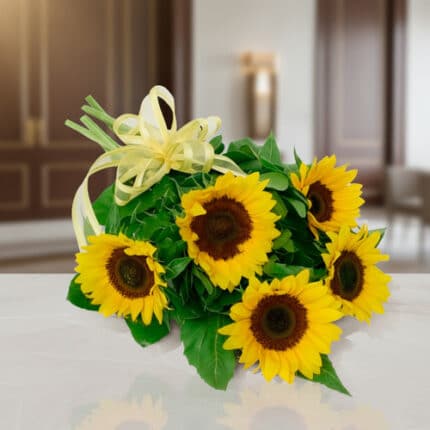 Ramo de girasoles amarillos con lazos decorativos sobre una mesa blanca en interior elegante