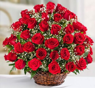 Ramo grande de rosas rojas frescas con paniculata blanca en una canasta de mimbre sobre superficie blanca