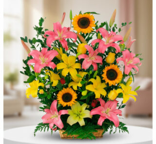 Arreglo de flores con lirios rosas y amarillos y girasoles en canasta de mimbre sobre mesa blanca en interior