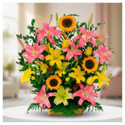 Arreglo de flores con lirios rosas y amarillos y girasoles en canasta de mimbre sobre mesa blanca en interior