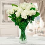 Ramo de rosas blancas frescas en un jarrón de cristal transparente sobre encimera de mármol, con fondo de salón elegante desenfocado