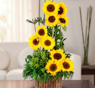 arreglo vertical de girasoles amarillos frescos con follaje verde en maceta de bambú sobre mesa en sala de estar luminosa