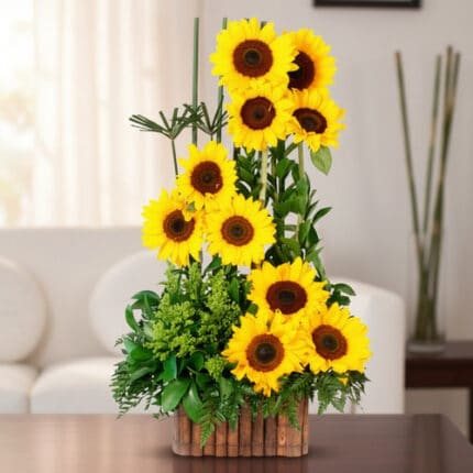 arreglo vertical de girasoles amarillos frescos con follaje verde en maceta de bambú sobre mesa en sala de estar luminosa