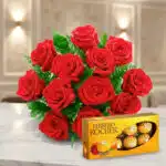 Ramo de rosas rojas sobre mesa de mármol junto a una caja de bombones Ferrero Rocher