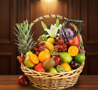 Cesta de mimbre llena de frutas frescas como piñas, naranjas, manzanas, uvas, kiwis y peras sobre una mesa de madera con fondo marrón