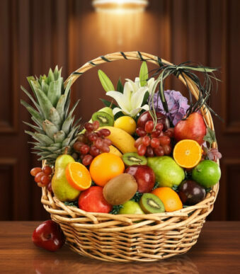 Cesta de mimbre llena de frutas frescas como piñas, naranjas, manzanas, uvas, kiwis y peras sobre una mesa de madera con fondo marrón