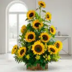 Arreglo de girasoles amarillos frescos en base rectangular de madera sobre mesa blanca en una sala luminosa