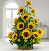 Arreglo de girasoles amarillos frescos en base rectangular de madera sobre mesa blanca en una sala luminosa