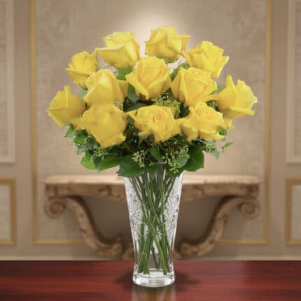 Ramo de rosas amarillas frescas en un jarrón de cristal tallado sobre una mesa de madera, con fondo interior elegante desenfocado