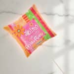 Globo cuadrado de helio con diseño colorido en tonos rosa, naranja y verde, decorado con flores y estrellas y la palabra ánimo en español, sobre fondo de mármol blanco