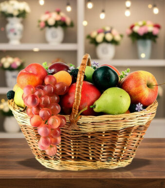 Canasta de mimbre llena de frutas variadas como uvas, manzanas, peras, duraznos y ciruelas sobre una mesa de madera con fondo de estantería decorada con flores y luces