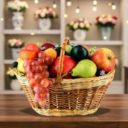 Canasta de mimbre llena de frutas variadas como uvas, manzanas, peras, duraznos y ciruelas sobre una mesa de madera con fondo de estantería decorada con flores y luces