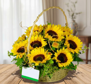 Arreglo floral de girasoles amarillos en canasta trenzada con asa, sobre mesa de madera en interior desenfocado