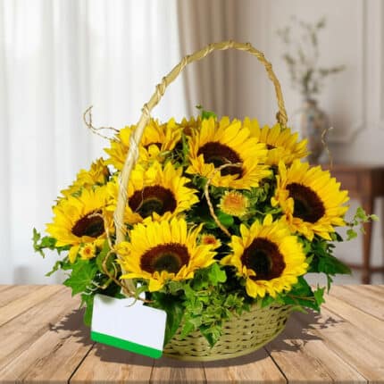 Arreglo floral de girasoles amarillos en canasta trenzada con asa, sobre mesa de madera en interior desenfocado