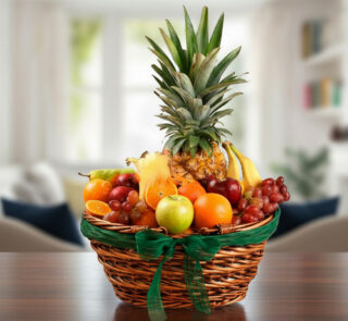 Canasta de mimbre con piña, uvas, manzanas, naranjas, plátanos y otras frutas variadas sobre una mesa de madera en sala desenfocada