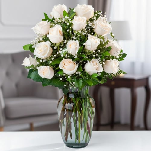 Ramo de rosas blancas en jarrón de cristal Arreglo de rosas blancas con follaje verde y paniculata en un jarrón de cristal sobre una mesa en una sala elegante