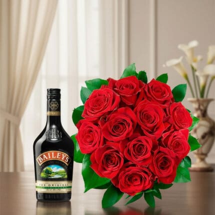 Botella de licor Baileys junto a un ramo de rosas rojas con hojas verdes sobre una mesa de madera, con cortinas claras y florero desenfocado al fondo