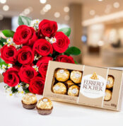 Ramo de rosas rojas con flores blancas pequeñas junto a una caja abierta de chocolates Ferrero Rocher sobre fondo desenfocado