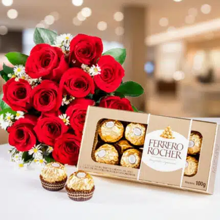 Ramo de rosas rojas con flores blancas pequeñas junto a una caja abierta de chocolates Ferrero Rocher sobre fondo desenfocado