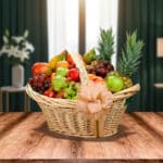 canasta de mimbre con lazo decorativo llena de frutas variadas como piñas, uvas, manzanas, peras y plátanos sobre mesa de madera con fondo de sala desenfocado