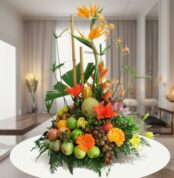 Arreglo de frutas frescas con flores tropicales de colores sobre una mesa blanca en una sala moderna