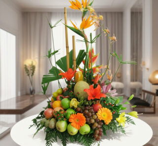 Arreglo de frutas frescas con flores tropicales de colores sobre una mesa blanca en una sala moderna