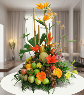 Arreglo de frutas frescas con flores tropicales de colores sobre una mesa blanca en una sala moderna