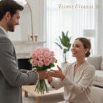 Hombre joven entregando un ramo de rosas rosas a una mujer sonriente sentada en una sala de estar elegante y luminosa