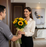 Mujer joven recibiendo un ramo de girasoles de un repartidor en la entrada de su casa