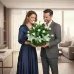 Hombre y mujer vestidos de forma elegante sostienen una canasta con rosas blancas y follaje verde en una sala de estar moderna y luminosa