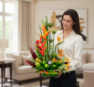 Mujer joven sostiene un arreglo floral tropical con flores naranjas, verdes y rojas en una sala de estar luminosa y moderna